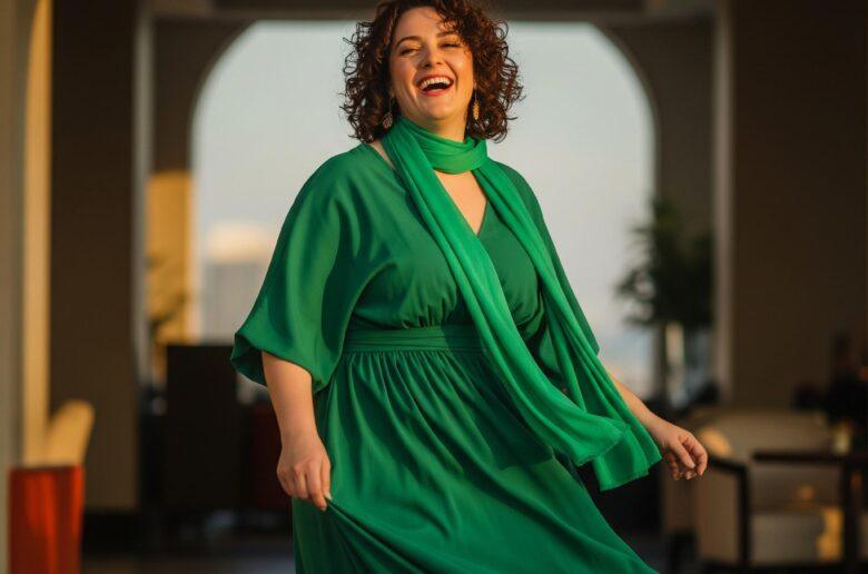 Lachende mollige Frau in einem gruenen Kleid
